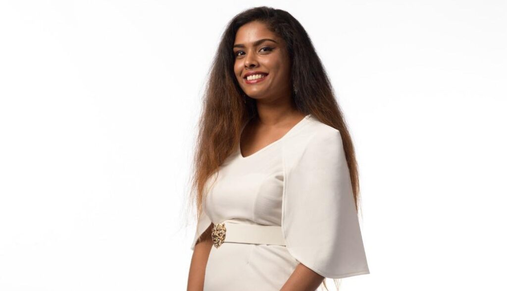 Dilani Selvanathan - Asian woman with hair going past her shoulders, wearing a white dress with belt and statement sleeves. 