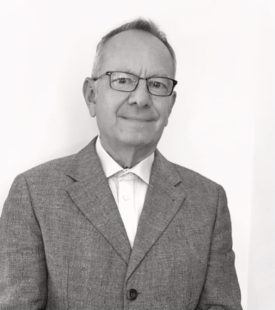 Radu P. Obreja - Black and white photo of a white man with very short grey hair wearing glasses, suit and white shirt with no tie.