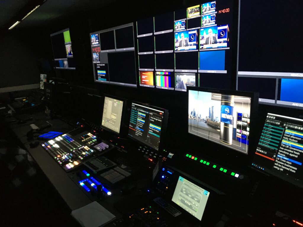 A TV gallery with monitors and lights shining in a dark bakground.
