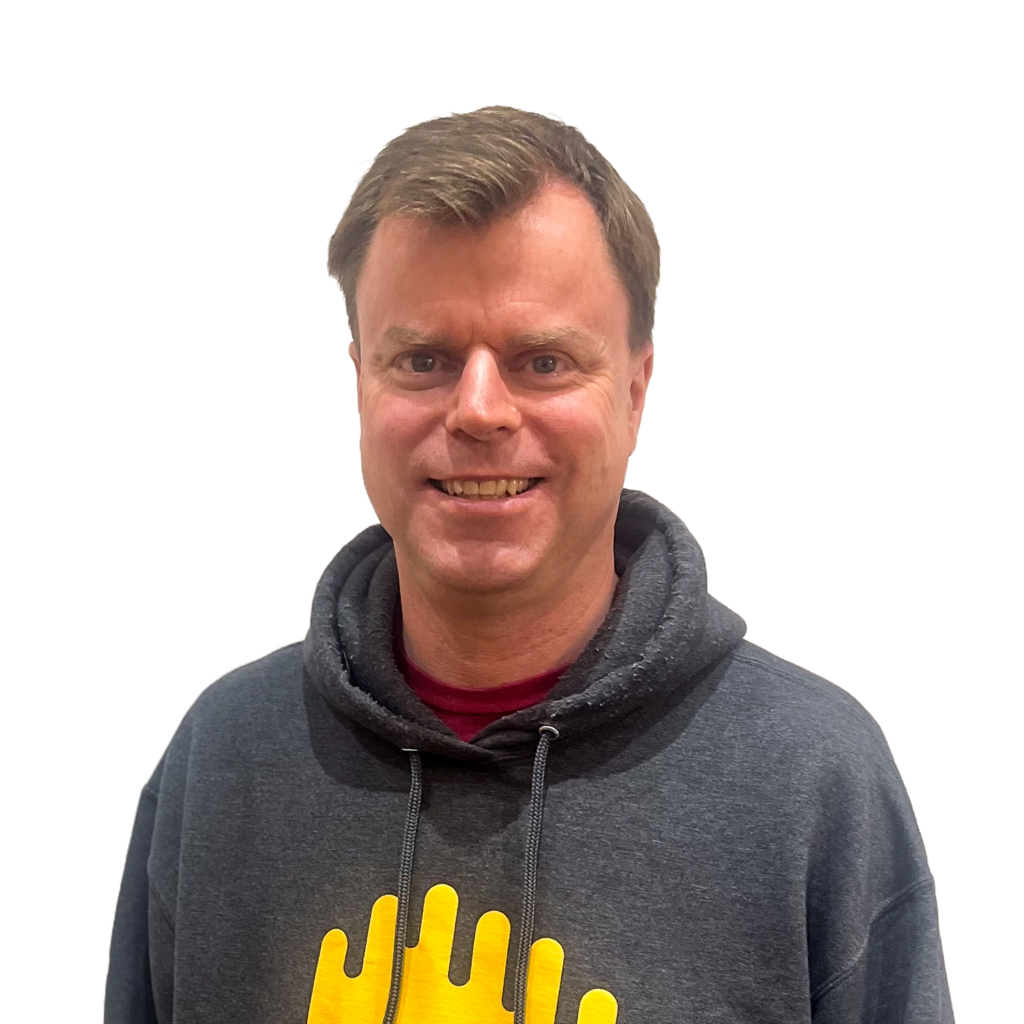 Dan McQuillin - white man with short brown hair, wearing a dark grey hoodie with dark yellow Broadcast Bionics waveform logo on the front.